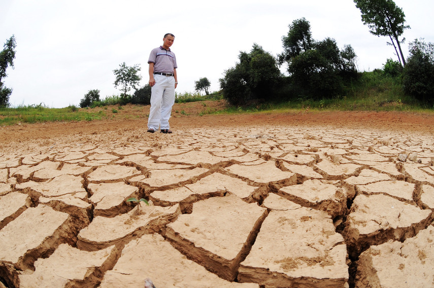 A villager looks at the bottom of a pond full of cracks due to drought in Xinhua County of central China&apos;s Hunan Province, July 30, 2011. Due to high temperature and lack of rainfalls, Hunan has been hit by lasting droughts in recent days. [Xinhua]