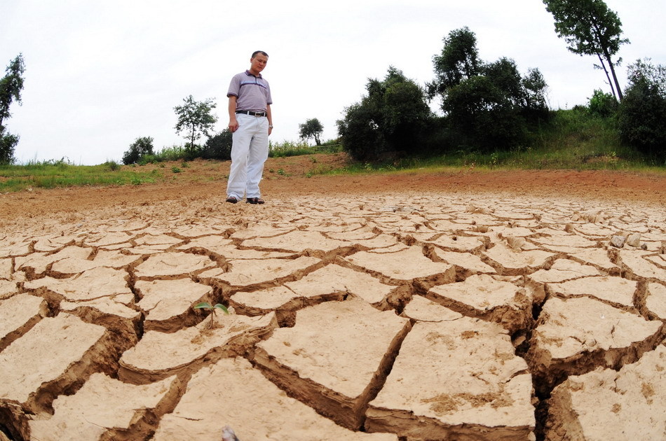 A villager looks at the bottom of a pond full of cracks due to drought in Xinhua county of Central China&apos;s Hunan province, July 30, 2011. Due to high temperature and the lack of rainfalls, 27 counties and cities in Hunan have been hit by lasting droughts in recent days, according to the province&apos;s flood control and drought relief Headquarters. [Xinhua]