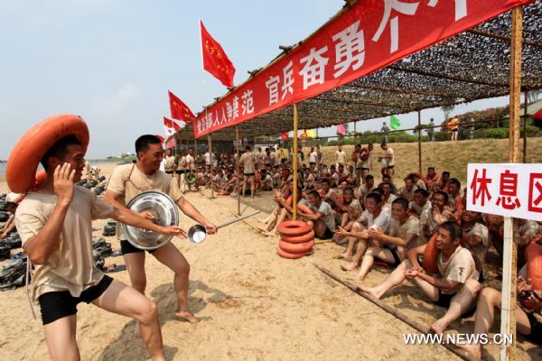 Two soldiers perform for their comrades during their break of a drill in Shanghai, east China, July 23, 2011. Soldiers of a detachment in Shanghai attended a series of drills in the scorching sunshine recently, aiming at strengthening minds and improving military skills. 