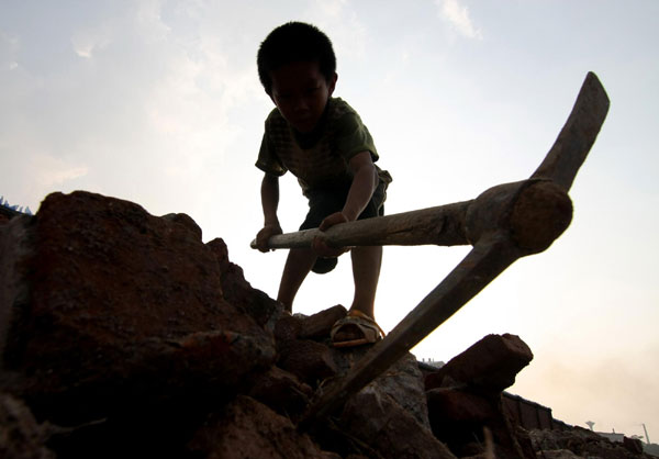 The 9-year-old, Xiong Sansan, digs scrap irons in an abandoned building site in Liuzhou city, South China's Guangxi Zhuang autonomous region, July 29, 2011.