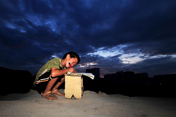 Xiong Sansan does his homework in Baisha, an urban village in Liuzhou city, South China's Guangxi Zhuang autonomous region, July 29, 2011.