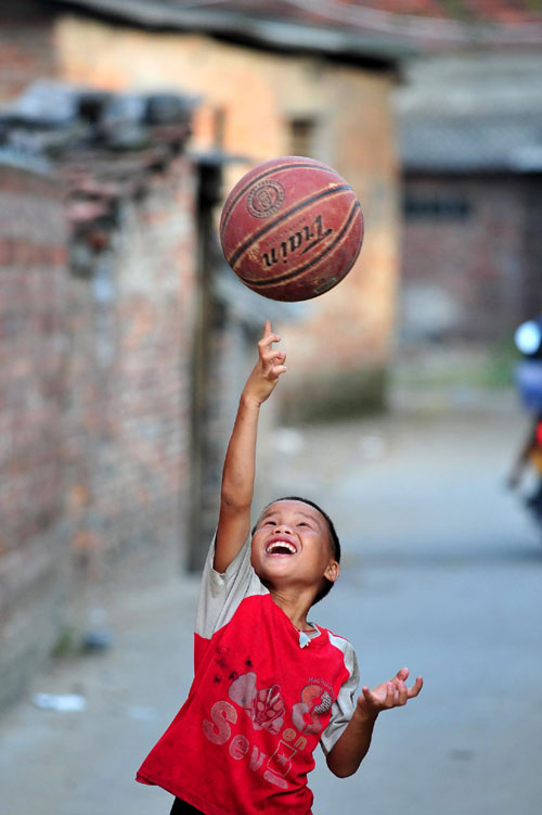 Xiong Sansan's good friend, Zhang Bin shows off his basketball skills in Baisha, an urban village in Liuzhou city, South China's Guangxi Zhuang autonomous region, July 29, 2011.