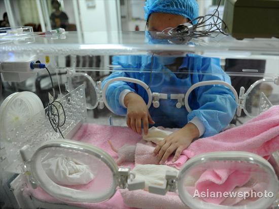 A researcher puts a newly-born panda cub into an incubator, Aug 2, 2011. [Asianewsphoto]