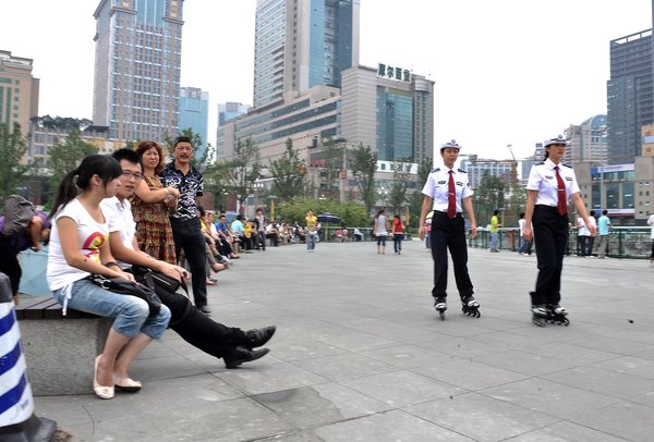 Female urban management officers, better known in China as chengguan, equipped with roller blades, patrol on duty at Tianfu Square in downtown Chengdu, Southwest China's Sichuan province, Aug 1, 2011. 
