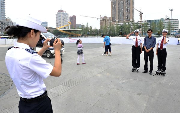 Female chengguan, wearing roller blades, pose for photos with a tourist at Tianfu Square in downtown Chengdu, southwest China's Sichuan province, Aug 1, 2011. [Photo/CFP] 