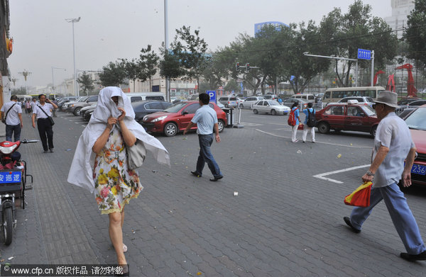 A woman shields herself from gales in Urumqi, Northwest China&apos;s Xinjiang Uygur autonomous region, Aug 3, 2011. [CFP]