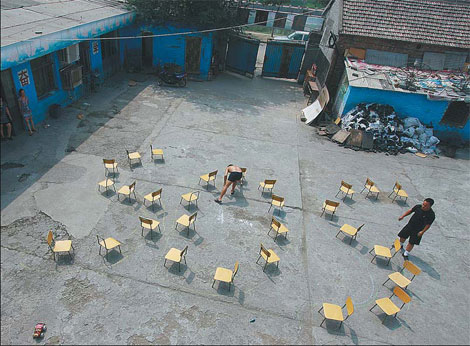 Luyuan Primary School principal Zhang Xiaohu (right) put chairs into the shape of SOS on Wednesday, appealing for help from the government and society after the school was forced to shut down. Hundreds of students could be left without a school. 