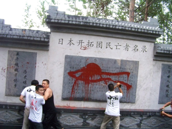 Three Chinese netizens splash red paint on a small wailing wall dedicated to Japanese immigrants who came to China from 1932 to 1945 in Fangzheng county, Northeast China's Heilongjiang province, on Wednesday. [Photo/China Daily]