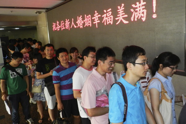 Couples line up to register at a marriage registry office in Beijing's Xicheng district, Aug 6, 2011, which in the Chinese lunar calendar falls on July 7, Chinese Lovers Day. The screen reads: 'We wish every newly-wed couple happiness.' [Photo/Xinhua] 