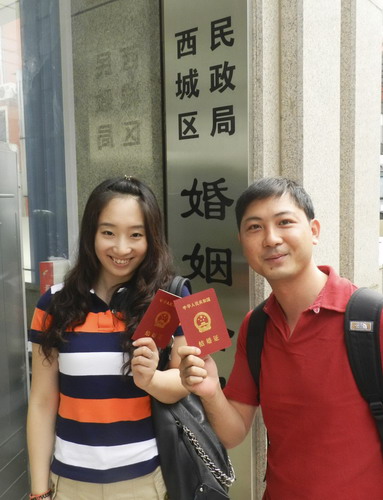 A newly-wed couple poses with their marriage certificates at a marriage registry office in Xicheng district, Beijing, Aug 6, 2011. [Photo/Xinhua]