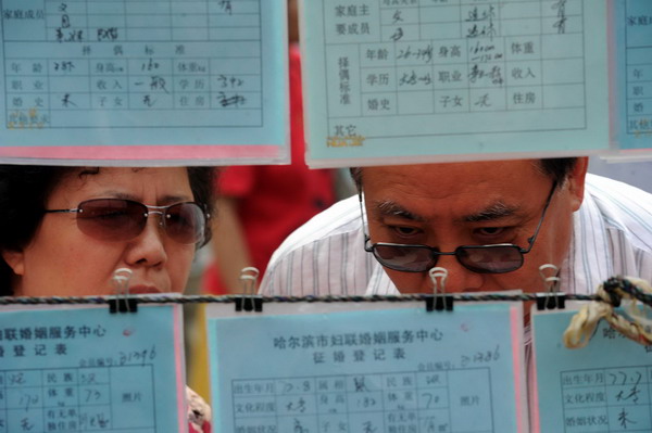 People look at ads hung on strings at a matchmaking fair held in Harbin, capital of Northeast China's Heilongjiang province, on Qixi, the Chinese Lovers Day, on Aug 6, 2011. [Photo/Xinhua]