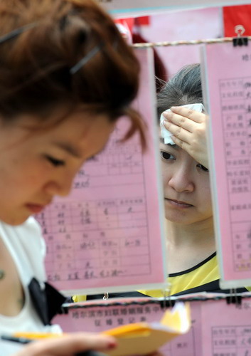 Single women look at and take notes from ads hung on strings at a matchmaking fair held in Harbin, capital of Northeast China's Heilongjiang province, on Qixi, the Chinese Lovers Day, on Aug 6, 2011. [Photo/Xinhua]