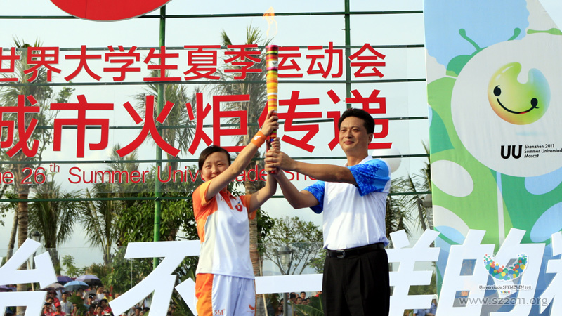 Zhang Wen, Vice mayor of Shenzhen, hands over the Universiade torch to Sun Ying, the No.1 torchbearer during the torch relay of the 26th Summer Universiade,in Shenzhen,China, August 7, 2011. 