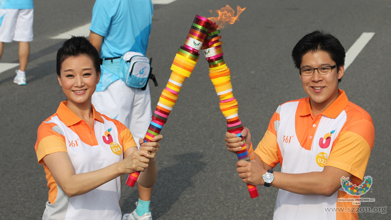 Famous singer Song Zuying, passes the Universiade flame to Huo Qigang,a famous Hongkong entrepreneur during the Torch Relay of the 26th Universiade,Shenzhen,China,Aug 7,2011. 