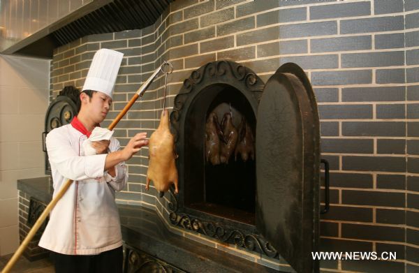 A staff member of Pianyifang, an honoured Beijing roast duck restaurant, cooks roast duck during the Second Qianmen Historic and Cultural Festival on Qianmen Street in Beijing, capital of China, Aug. 7, 2011. The 10-day festival kicked off here on Sunday. (Xinhua/Zhao Bing) (zl) 