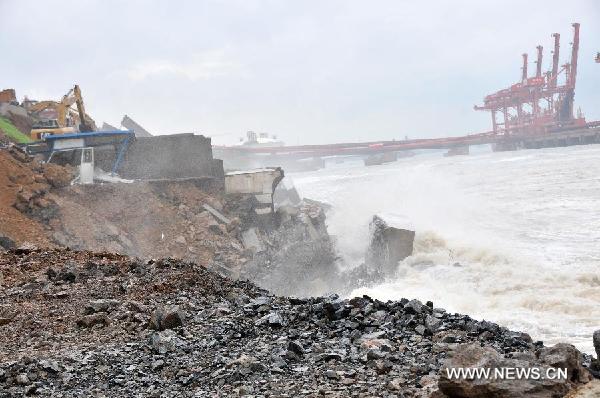 Photo taken on Aug. 8, 2011 shows the breached dike which guards a chemical plant in Dalian City, northeast China's Liaoning Province. Workers driving forklifts rushed to repair the dike breached by powerful waves triggered by a tropical storm on Monday over fears of a toxic spill from a petrochemical plant located behind the dike. [Xinhua] 