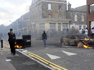 A masked rioter gestures on a street in Hackney, east London, Britain, Aug. 8, 2011. Rioting starting late Saturday appeared spreading across London on Monday, with vandalising, arson and looting taking place in various London communities. [Zeng Yi/Xinhua] 