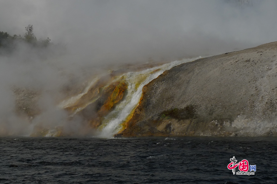 The heavy runoff from the 200-by-300-foot (61 by 91 m) wide Excelsior Geyser to the Firehole River, with a speed of 4,000 US gallons (15,000 L; 3,300 imp gal) per minute. Thermophilic bacteria stain the riverbank into the orange color. As the first national park in the world, Yellowstone National Park is well-known for its wildlife and many geothermal features. [Photo by Xu Lin / China.org.cn]