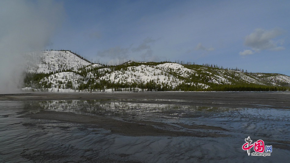 A view of Opal Pool and the far-away snow mountains in Yellowstone National Park, Wyoming, US. As the first national park in the world, Yellowstone National Park is well-known for its wildlife and many geothermal features. [Photo by Xu Lin / China.org.cn]