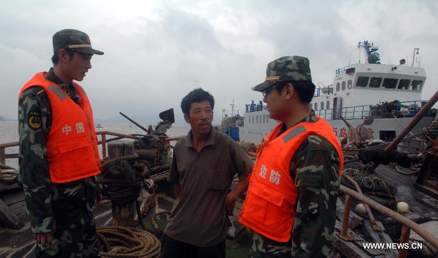 Soldiers of Chinese border guard check a fishing boat in Dalian, a coastal city in northeast China's Liaoning Province, as the Typhoon Muifa approaches the coast of the province on Aug. 8, 2011. [Xinhua]