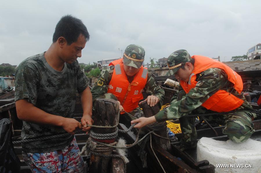 Soldiers of Chinese border guard help a fisherman to fix his fishing vessel on the dock in Dalian, a coastal city in northeast China's Liaoning Province, as the Typhoon Muifa approaches the coast of the province on Aug. 8, 2011. [Xinhua]