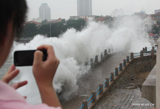A traveller takes photo of the big waves hitting the bank of Qingdao, east China's Shandong Province, Aug. 8, 2011. More than 360,000 people were evacuated in Shandong Province on Monday as tropical storm Muifa continues to move along the country's eastern coast.