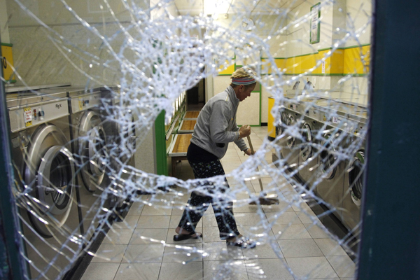 A worker cleans a laundry after overnight rioting and looting in the neighbourhood of Toxteth in Liverpool, northern England August 10, 2011. [Xinhua]