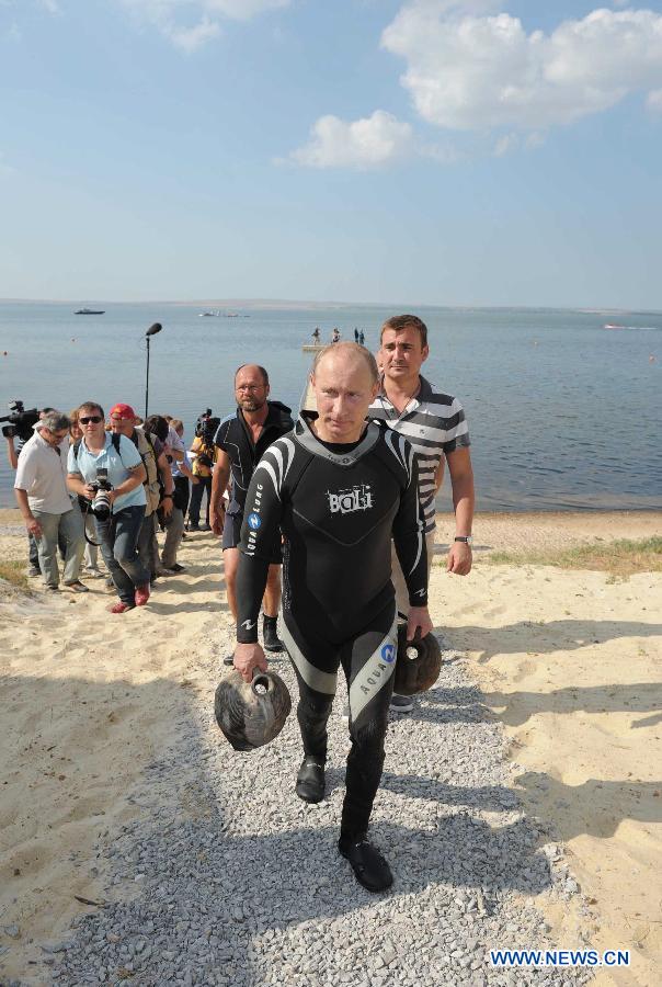 Russian Prime Minister Vladimir Putin carries artifacts he recovered whilst diving at an archaeological site off the Taman peninsular in southern Russia August 10, 2011. (Xinhua/Reuters Photo)