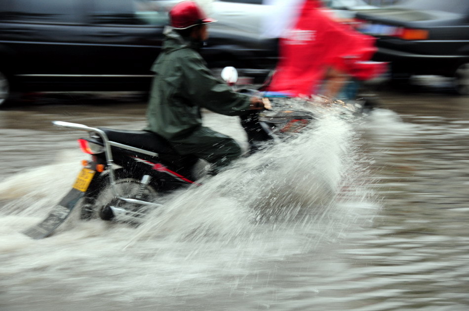 A citizen rides on a flooded road after a heavy rain hit Linyi, east China's Shandong Province, Aug. 11, 2011. According to the local meterological authority, another heavy rainfall is expected to hit the region in the next three days. [Xinhua]