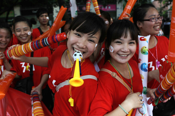 Shenzhen residents pose for pictures as they watch the torch relay for the 2011 Universiade on Thursday in the city's Longgang area. The Shenzhen Universiade will officially open on Friday, attracting about 7,800 athletes and officials from all over the world.