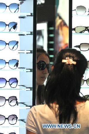 A girl tries glasses at a tax-free shop in Sanya, south China's Hainan Province, Aug. 12, 2011.