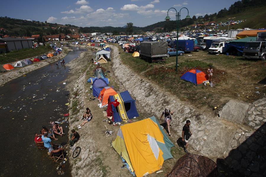 People take a rest in camping area beside the Bjelica River during the 51st Guca Trumpet Festival in western village Guca of Serbia on Aug. 13, 2011. About half million visitors came to Guca this year to attend the biggest trumpet festival in the world. (Xinhua/Marko Rupena)