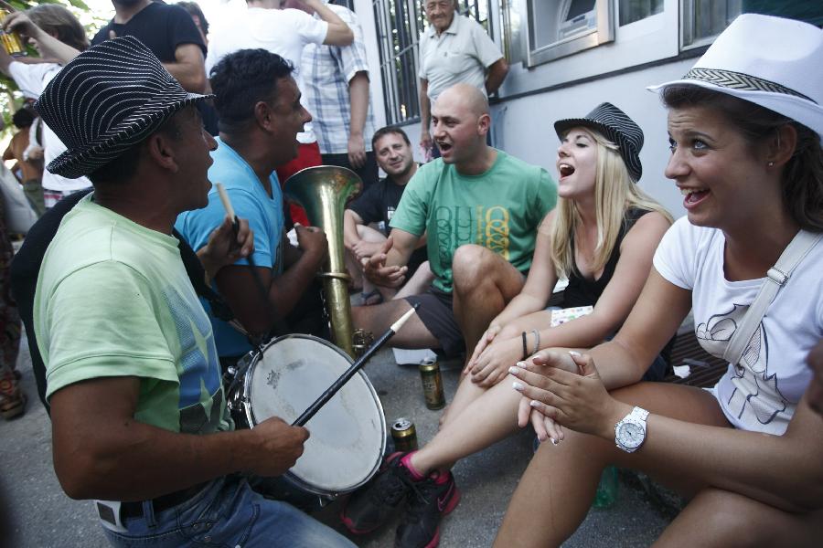 People enjoy the atmosphere during the 51st Guca Trumpet Festival in western village Guca of Serbia on Aug. 13, 2011. About half million visitors came to Guca this year to attend the biggest trumpet festival in the world. [Xinhua/Marko Rupena]