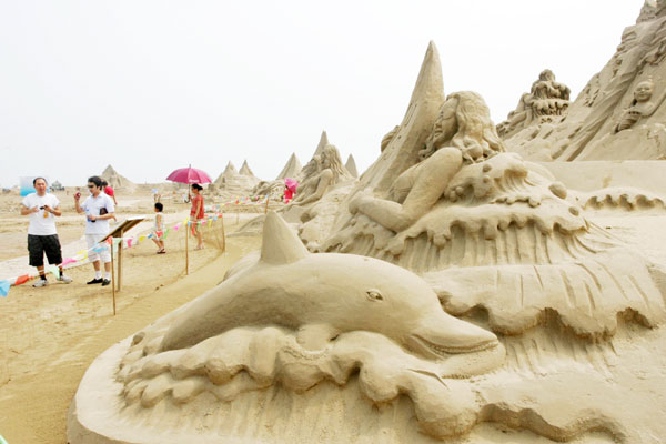 Tourists watch sand sculptures in a sand sculpture park in Weifang, Shandong province on August 14, 2011. 