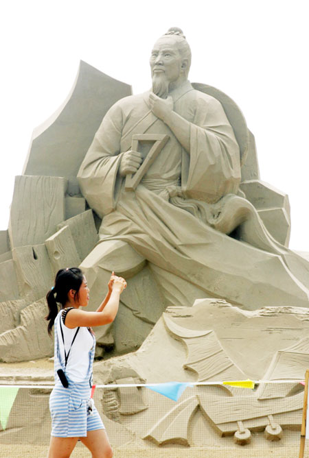 A tourist takes photos of the sand sculpture in the park on August 14, 2011. 