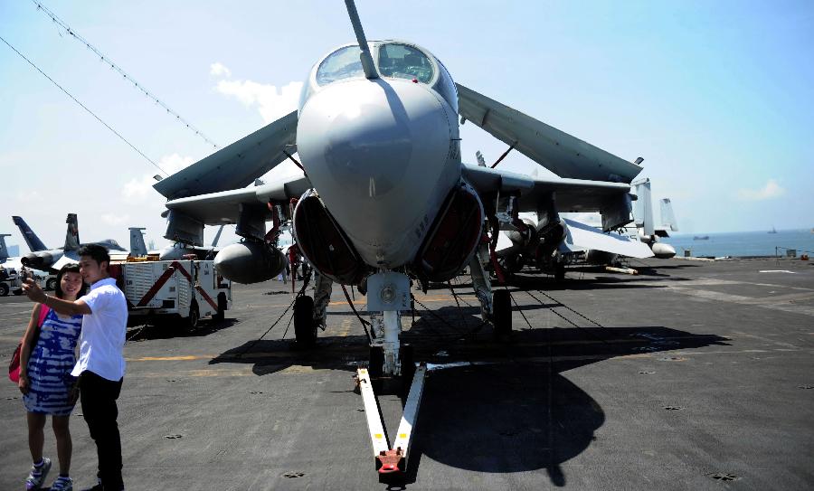 Visitors take photo in front of plane on the USS Ronald Reagan Aircraft Carrier in Hong Kong, Aug. 13, 2011. The USS Ronald Reagan Aircraft Carrier and its three support ships arrived in Hong Kong on Friday for a four-day port visit, which is its fourth visit here. [Chen Xiaowei/Xinhua]