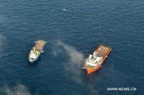 Two vessels clean up leaked oil on the sea surface around the C platform of the Penglai 19-3 oilfield in Bohai Bay, July 11, 2011. China's State Oceanic Administration (SOA) has urged investigators to speed up the handling of the oil leak at the B and C platforms of the oilfield in Bohai Bay that is being operated by the ConocoPhillips China (COPC).