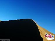 Photo taken on Aug. 25, 2011 shows the adjacent Mingsha Mountain Dunes (Singing-Sand Dunes) in Dunhuang City, northwest China's Gansu Province.  The famous tourist attraction Mingsha Mountain Dunes, which is six kilometers south of Dunhuang City, has moved towards Yueya Spring for about 8 to 10 meters in the past 15 years due to the geological movement, according to the latest statistics. [China.org.cn]