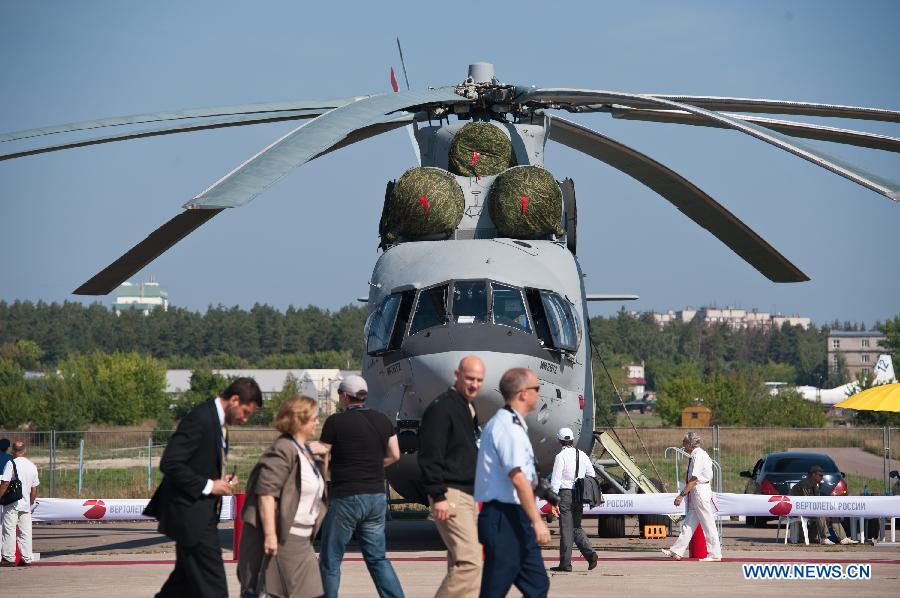 Vistors walk past a Mig-26T2 heavy transport helicopter during the Tenth Russia National Aerospace Exhibition in Moscow, Russia on Aug. 16, 2011. The Exhibition will last for six days, and 793 companies from 40 nations and regions participated. [Jiang Kehong/Xinhua]