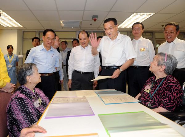 Chinese Vice Premier Li Keqiang (C) greets senior ladies during a visit to an elders' home at the Wong Cho Tong Social Service Building in Hong Kong, south China, Aug. 16, 2011. (Xinhua/Li Tao) (ljh) 