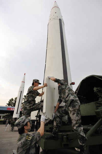 Soldiers of the Second Artillery Force install the empennage (the tail assembly) in the missile before launching it. [Photo/Xinhua] 