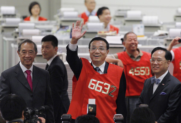 Vice-Premier Li Keqiang waves during a visit to the Hong Kong Stock Exchange on Wednesday. Li was accompanied by Ronald Arculli (left), chairman of the exchange, and Hong Kong Chief Executive Donald Tsang.  