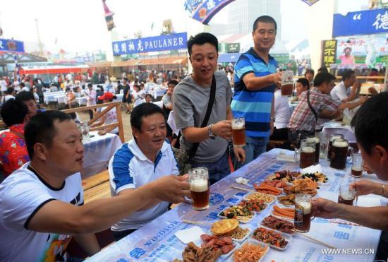 People drink beer at the 21st International Beer Festival at the beer city in Qingdao, east China&apos;s Shandong Province, Aug. 14, 2011. Qingdao&apos;s 21st International Beer Festival, a 16-day event, opened on Saturday, in which over 200 kinds of beer products of 20 well known brands are presented for beer lovers. A total of 77 tons of beer were sold during its first day. [Li Ziheng/Xinhua]