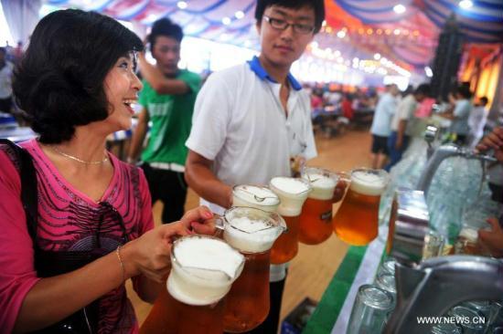 People buy beer at the 21st International Beer Festival at the beer city in Qingdao, east China's Shandong Province, Aug. 14, 2011. Qingdao's 21st International Beer Festival, a 16-day event, opened on Saturday, in which over 200 kinds of beer products of 20 well known brands are presented for beer lovers. A total of 77 tons of beer were sold during its first day. [Li Ziheng/Xinhua]