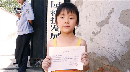 Wang Liming, a first-grade pupil at New Hope School, which was closed by education authorities in Beijing's Haidian district, holds a notice that says she can start classes at a public school on Aug 26. 