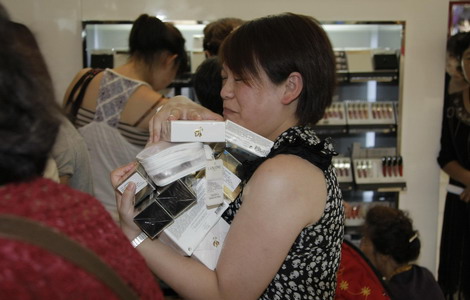 A woman carrying an armload of international perfumes and other cosmetic products makes her way toward a cashier at a duty-free shop in Sanya, South China's Hainan province. Foreign fragrance makers control 60 percent of the Chinese perfume market. [China Daily]