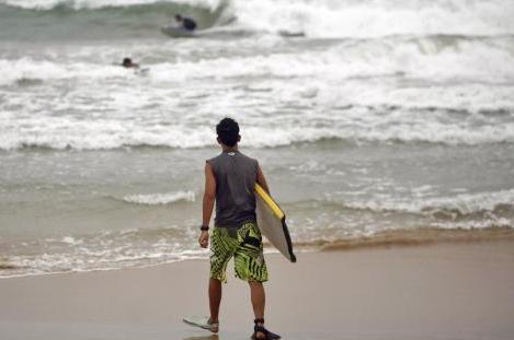 A surfer walks into the ocean as tropical storm Irene approaches the island in Luquillo, Puerto Rico.  