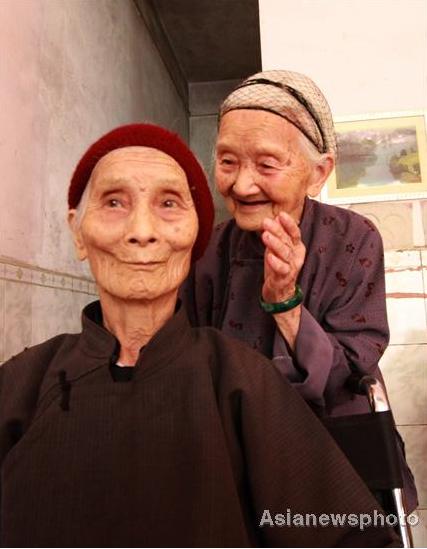 Huang Magan (right), 106, talks to her husband's 103-year-old second wife Huang Maxue at their home in Ping'an village, Bama Yao autonomous county, South China's Guangxi Zhuang autonomous region, August 21, 2011. 