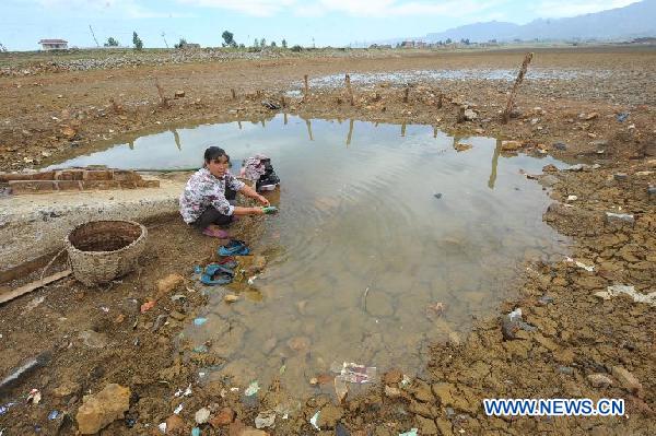 A housewife wash clothes at the dried-up Dongjin Reservior in Huangzhulin Village of Zhaotong City, southwest China&apos;s Yunnan Province, Aug. 23, 2011. A lingering drought has withered up almost 220,000 hectares of crops and dried up 15 rivers in Zhaotong, leaving at least 190,000 people and 28,000 livestock short of drinking water. [Xinhua]