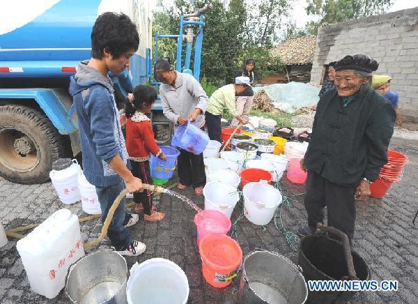 Residents collect water from a tank truck in Shuitang Village of Zhaotong City, southwest China&apos;s Yunnan Province, Aug. 23, 2011. A lingering drought has withered up almost 220,000 hectares of crops and dried up 15 rivers in Zhaotong, leaving at least 190,000 people and 28,000 livestock short of drinking water. 